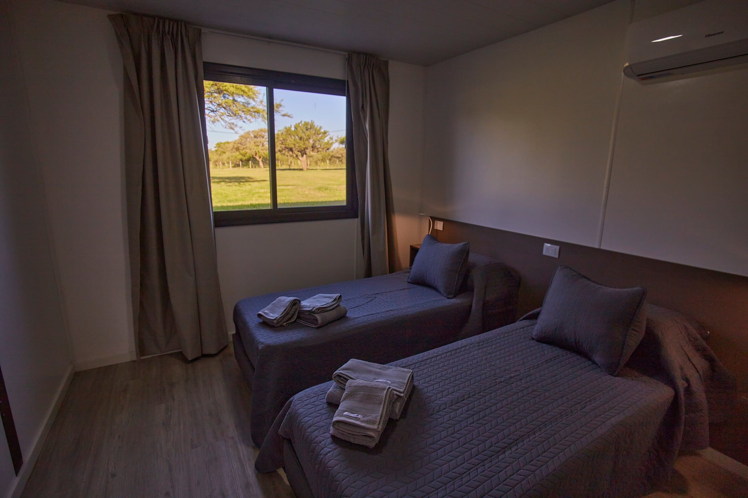 Dos camas individuales junto a la ventana con vista al monte