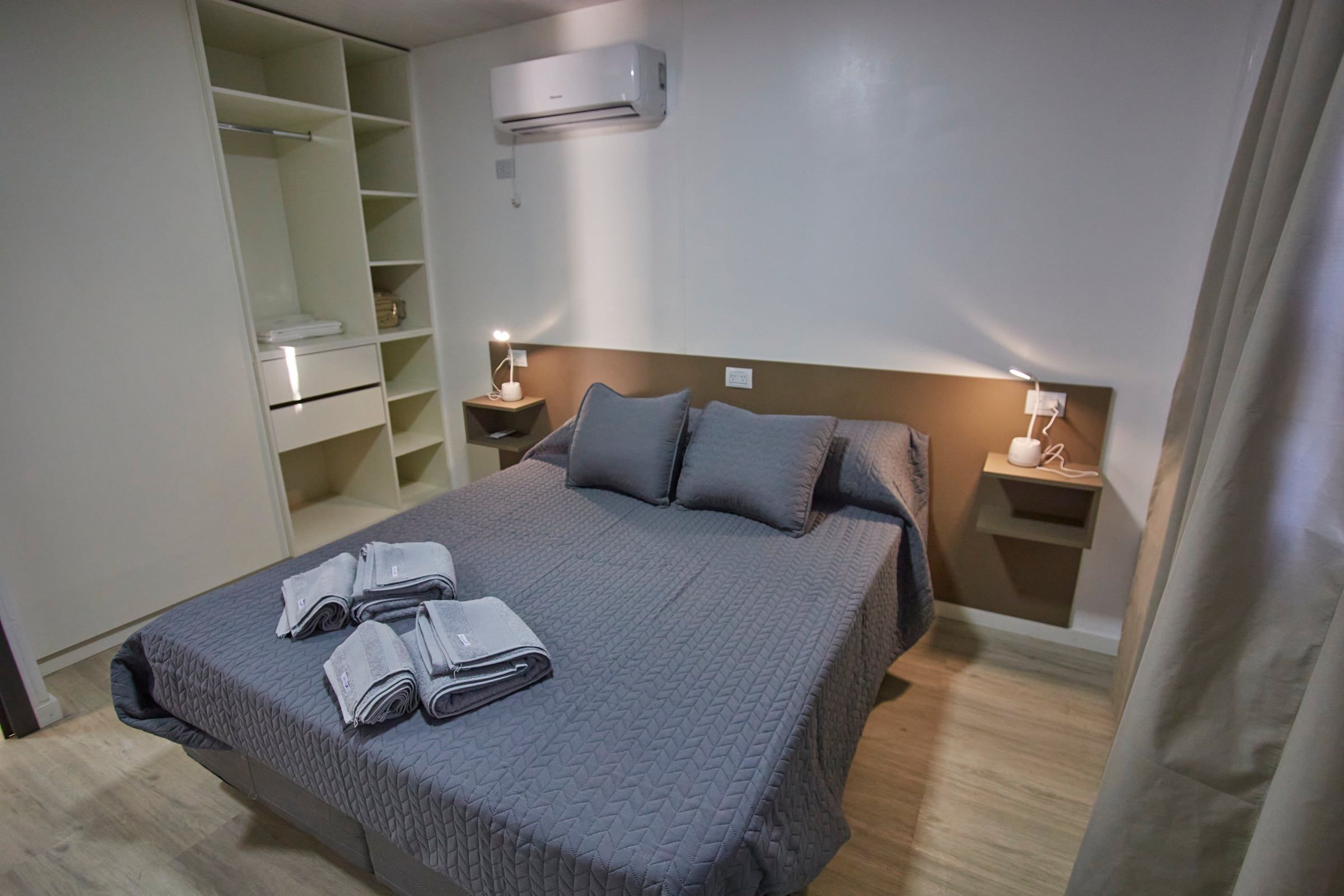 Cama matrimonial con mesas de luz y aire acondicionado