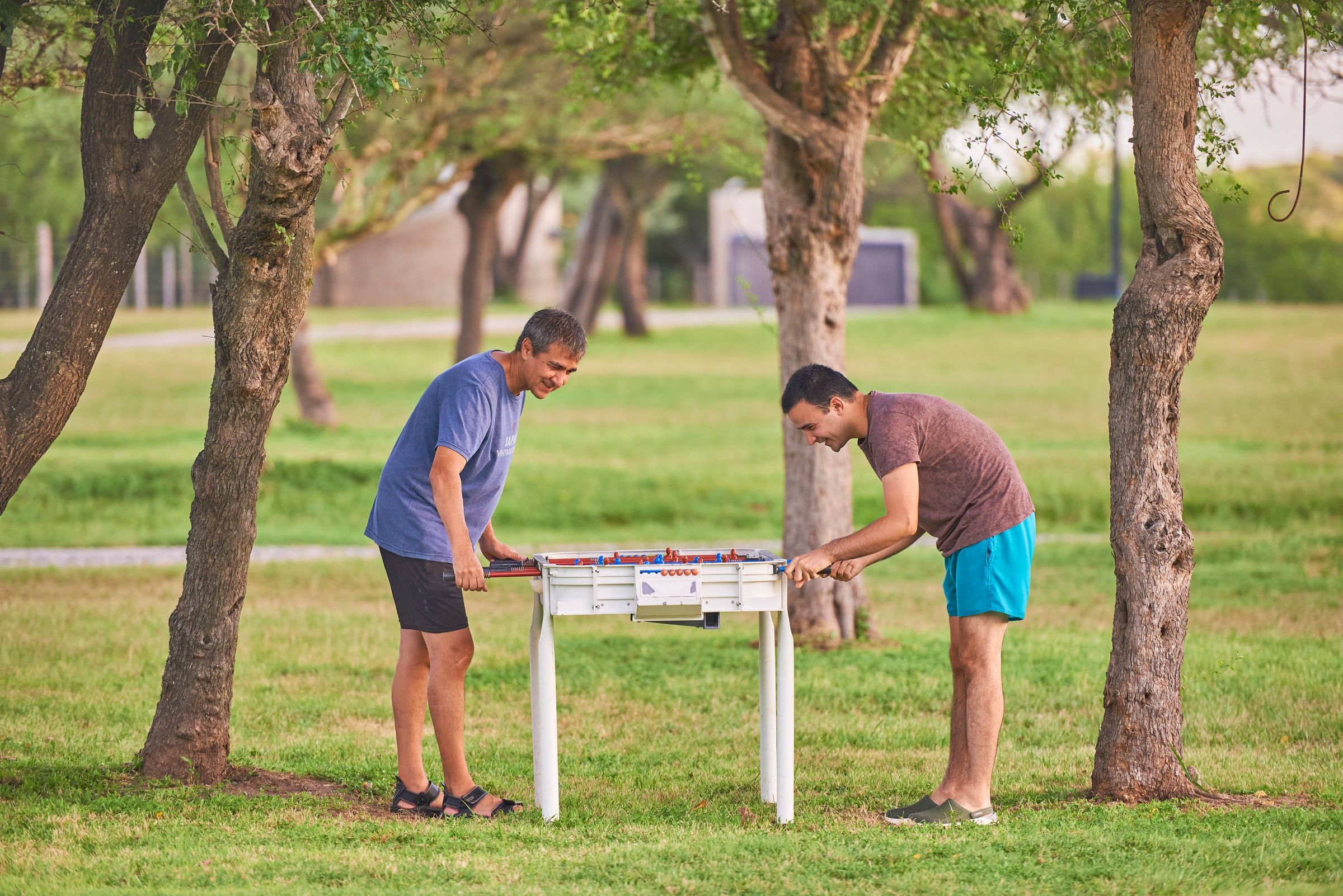 Dos amigos jugando al metegol bajo los árboles