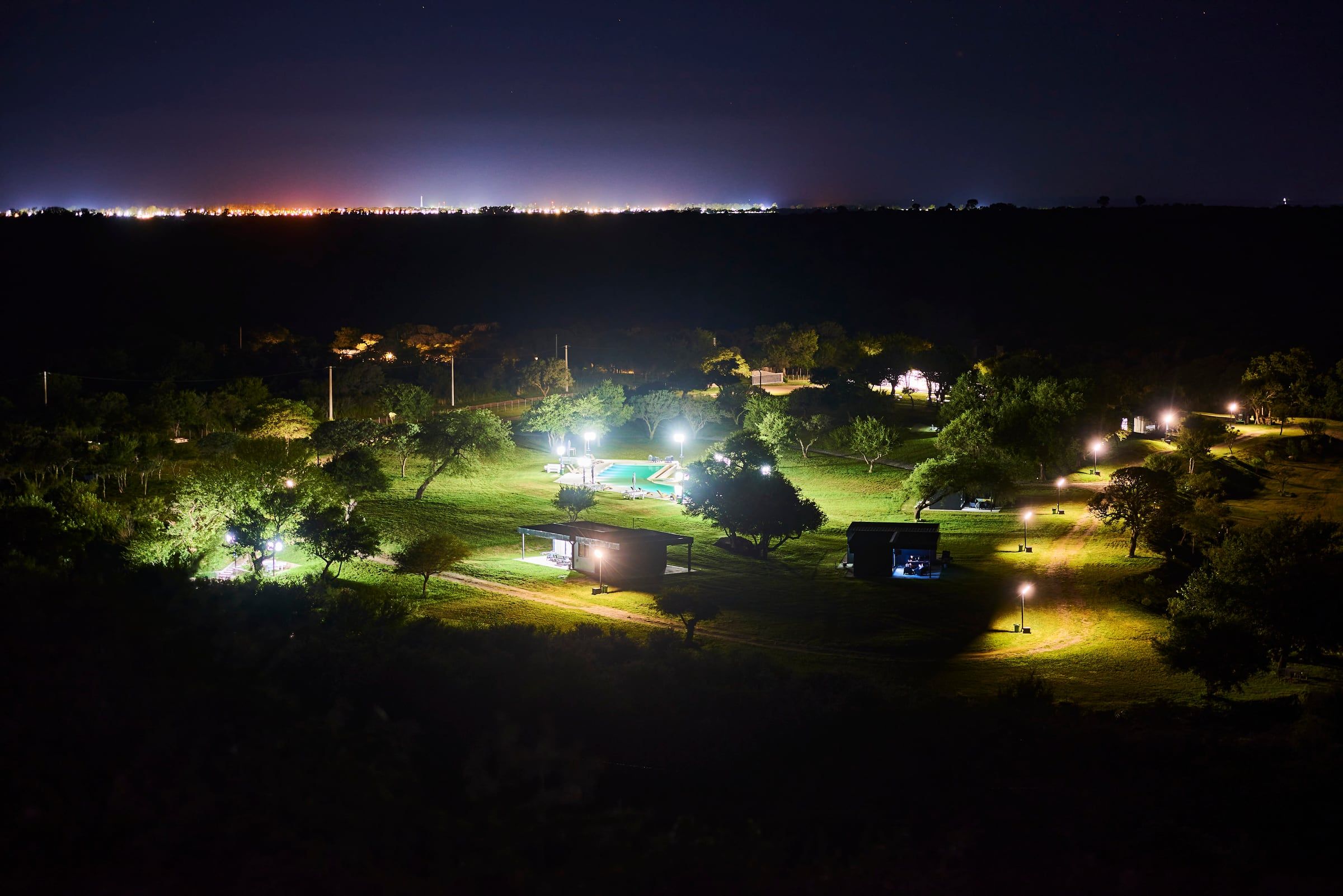 El predio de noche, con los caminos y la pileta iluminados